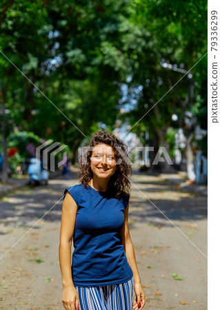 Beautiful curly brunette girl model walks on a summer day 79336299