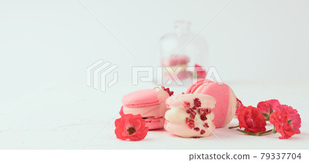 baked red strawberry macarons and rosebuds on a white table, gourmet almond flour dessert 79337704