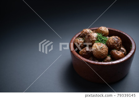 close up of roasted potatoes with herbs in clay bowl on black background close up of roasted potatoes with herbs in clay bowl on black background 79339145