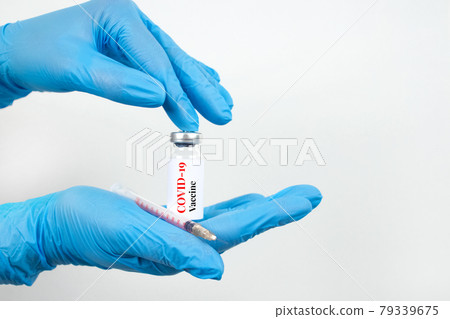 Female scientist or doctor hands holding vial dose of COVID-19 vaccine with syringe against white background with copy space - prevention coronavirus, global vaccination concept. Selective focus Female scientist or doctor hands holding vial dose of COVID-19 vaccine with syringe against white background with copy space - prevention coronavirus, global vaccination concept. Selective focus 79339675