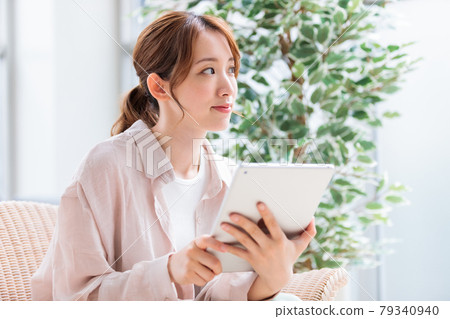 一位年輕女子在平板電腦上閱讀並瀏覽互聯網 79340940