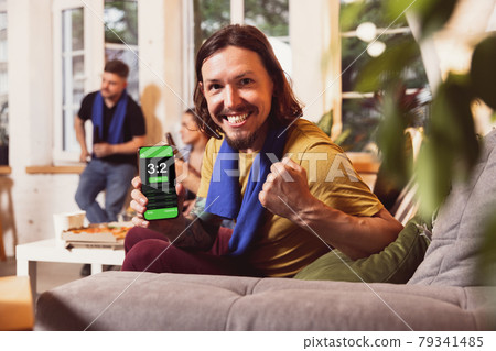 Bet for winner. Young men watching TV, sport match together. Concept of friendship, leisure activity, emotions Bet for winner. Young men watching TV, sport match together. Concept of friendship, leisure activity, emotions 79341485