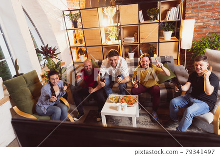 Bet for winner. Young men watching TV, sport match together. Concept of friendship, leisure activity, emotions Bet for winner. Young men watching TV, sport match together. Concept of friendship, leisure activity, emotions 79341497