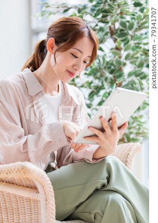一位年輕女子在平板電腦上閱讀並瀏覽互聯網 一位年輕女子在平板電腦上閱讀並瀏覽互聯網 79341707