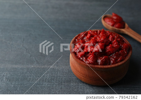 Wooden bowl and spoon with tomato paste on dark wooden background Wooden bowl and spoon with tomato paste on dark wooden background 79342162