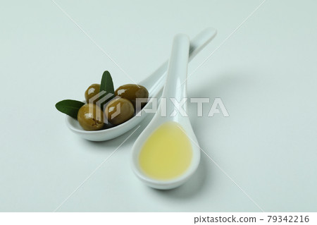 Spoons with olives and oil on white background Spoons with olives and oil on white background 79342216