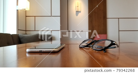 Smartphone and glasses placed on a wooden table, modern interior Smartphone and glasses placed on a wooden table, modern interior 79342268