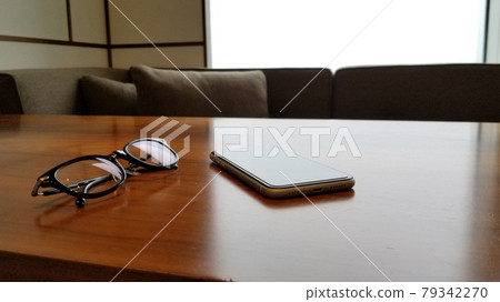 Smartphone and glasses placed on a wooden table, modern interior Smartphone and glasses placed on a wooden table, modern interior 79342270