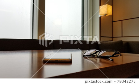 Smartphone and glasses placed on a wooden table, modern interior Smartphone and glasses placed on a wooden table, modern interior 79342273