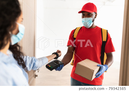 Black man holding POS machine lady paying with smart watch 79342385