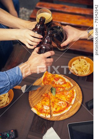 Cheers. Four young people, sportive fans meeting together in bar, pub. Concept of friendship, leisure activity, emotions and sport event 79342642