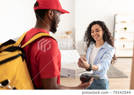 Black deliveryman holding pizza boxes and pos terminal for client Black deliveryman holding pizza boxes and pos terminal for client 79342844