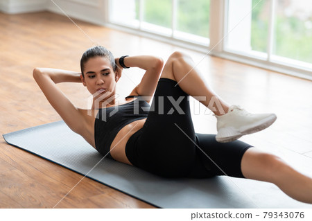 Smiling Young Woman Doing Twist Crunches Exercise Smiling Young Woman Doing Twist Crunches Exercise 79343076