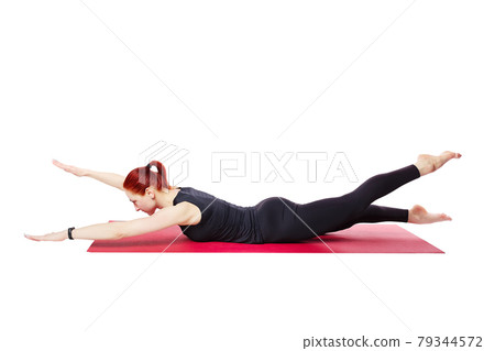Pilates or yoga. A slender athletic girl performs an exercise to strengthen the back muscles. Visual 79344572
