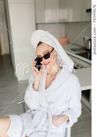 Woman in white robe stay near the window and on bed in hotel room 79344676