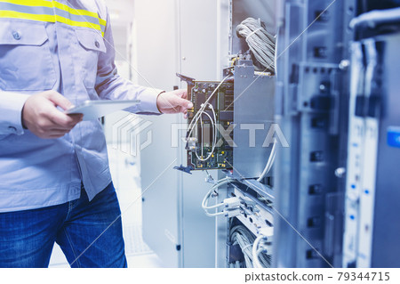 Technician using digital tablet in server room, repair card mainboard checking network link status 79344715