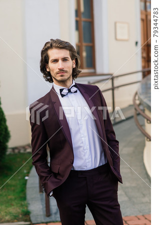 Stylish handsome man with beard, wearing suit jacket and shirt, outdoors on the city street. 79344783