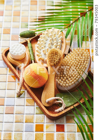 Jars of cream for face and body care, gold eye patches and serum with gold, jade roller massager gau-sha and massager and body brush against background of tile mosaic 79345003