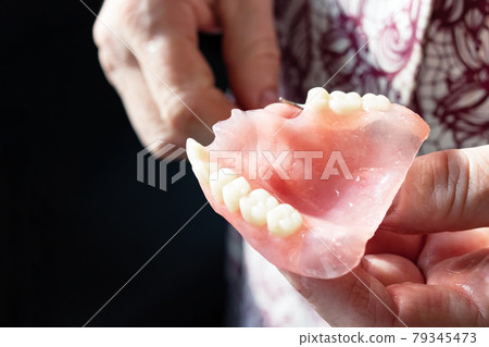 False jaw in womans hand close up False jaw in womans hand close up 79345473
