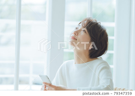 Middle-aged woman operating a smartphone in the room 79347359