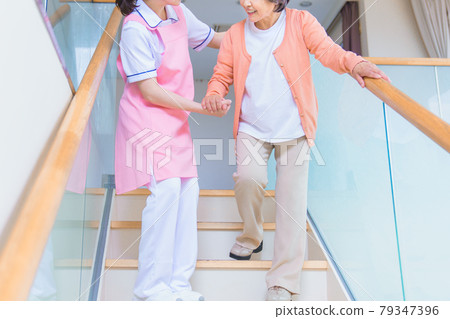 Senior women and care staff on the stairs 79347396