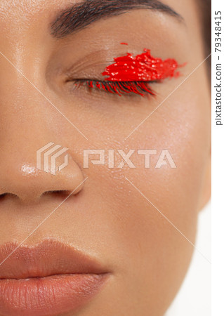 Close up beauty of a half face of a woman with wet radiant skin and big gray eyes. Fashionable natural makeup and wet facial hair. Pink lipstick with kissed lips 79348415