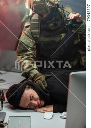 Police officer seizing one of cyber criminals 79348597
