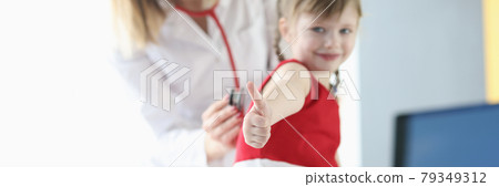 Little girl showing thumb up during doctors checkup closeup Little girl showing thumb up during doctors checkup closeup 79349312