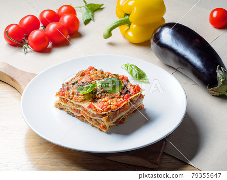Piece of lasagna on white plate with vegetables Piece of lasagna on white plate with vegetables 79355647
