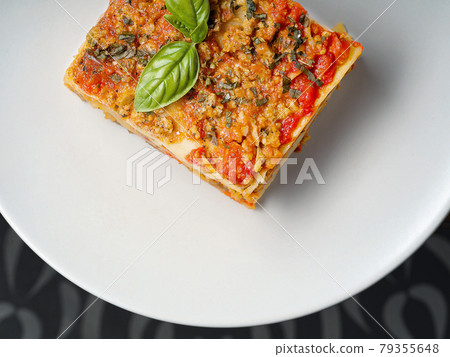 Piece of lasagna with a basil leaf on white plate Piece of lasagna with a basil leaf on white plate 79355648