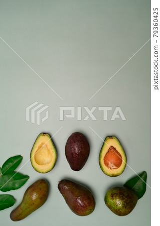 Whole and half avocado on green background. Whole and half avocado on green background. 79360425