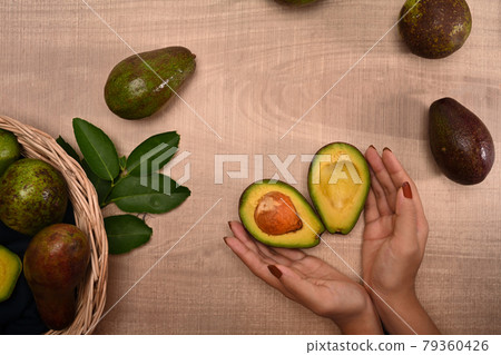Woman holding avocado on wooden background. Woman holding avocado on wooden background. 79360426