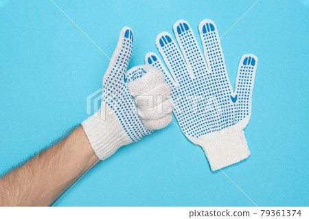 The man puts on protective construction gloves. Gloves made from durable fabric. Safety engineering. Symbol like. 79361374