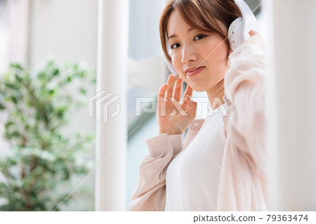 Young woman listening to music with headphones Young woman listening to music with headphones 79363474