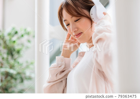 Young woman listening to music with headphones 79363475