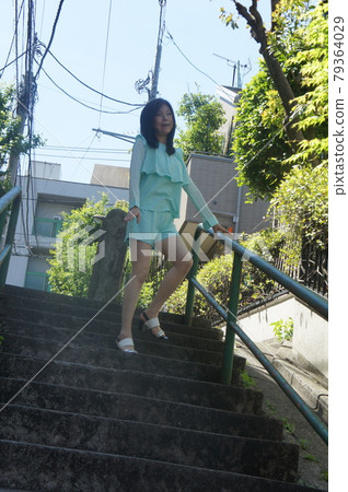 A tall woman walking through the streets with stairs 79364029
