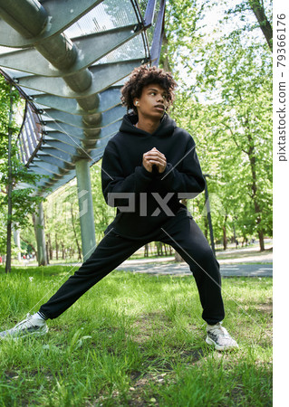 Man warming up before the workout at the spring park at the morning around the green trees Man warming up before the workout at the spring park at the morning around the green trees 79366176