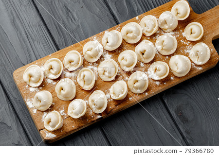 Raw meat dumplings on wooden board on table 79366780