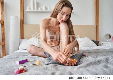 Girl with vitiligo making fashionable manicure at home while sitting at the bed Girl with vitiligo making fashionable manicure at home while sitting at the bed 79366844