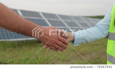 Close up of handshake on solar panel background. Female engineer shakes hands with partner in agreement. Concept.renewable energy, technology, electricity, service, green. Close up of handshake on solar panel background. Female engineer shakes hands with partner in agreement. Concept.renewable energy, technology, electricity, service, green. 79367042
