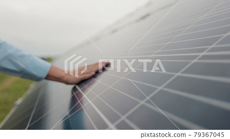 Close up of a young woman engineer hand is checking the operation of sun and cleanliness of photovoltaic solar panels on a sunset. Concept.renewable energy, technology, electricity, service, green. Close up of a young woman engineer hand is checking the operation of sun and cleanliness of photovoltaic solar panels on a sunset. Concept.renewable energy, technology, electricity, service, green. 79367045