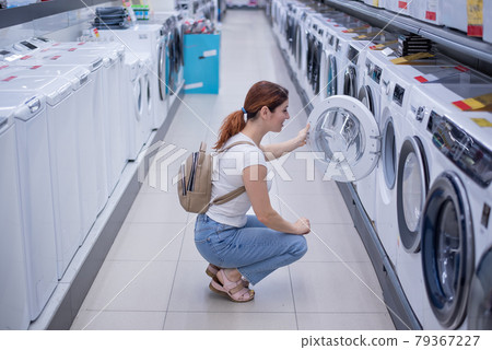 Caucasian woman chooses a washing machine in a home appliances store Caucasian woman chooses a washing machine in a home appliances store 79367227