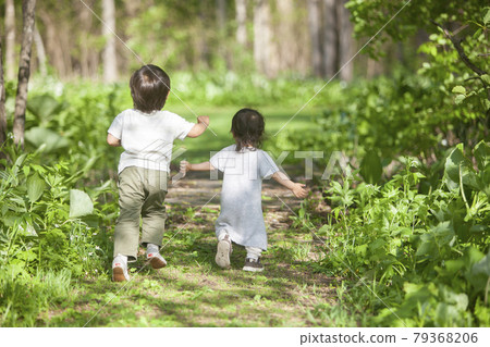 Brothers and sisters running down a forest path 79368206