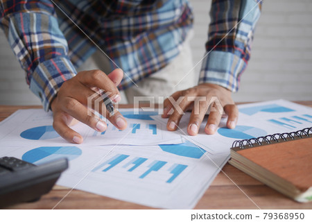 man hand with pen analyzing bar chart on paper  79368950