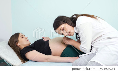 Doctor puts fetoscope on pregnant woman belly in hospital Doctor puts fetoscope on pregnant woman belly in hospital 79368984