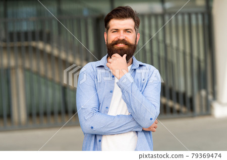 His beard needs a barber. Happy barber on urban background. His beard needs a barber. Happy barber on urban background. 79369474
