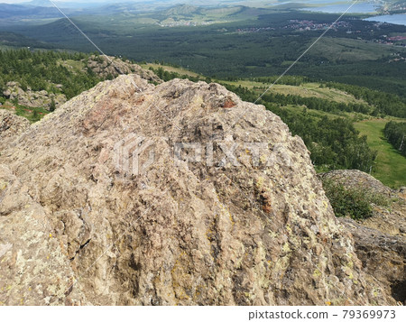 A large stone on the background of mountains with trees 79369973