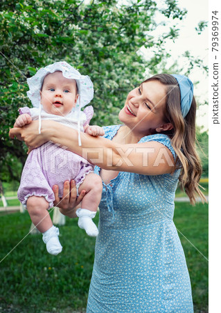 Young woman with loose fair hair rocks in arms baby girl 79369974