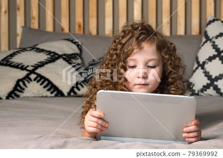 Interested preschooler girl watches cartoons on tablet 79369992