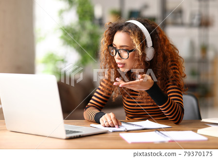 Focused afro american female having video call while working remotely or studying online on laptop from home 79370175